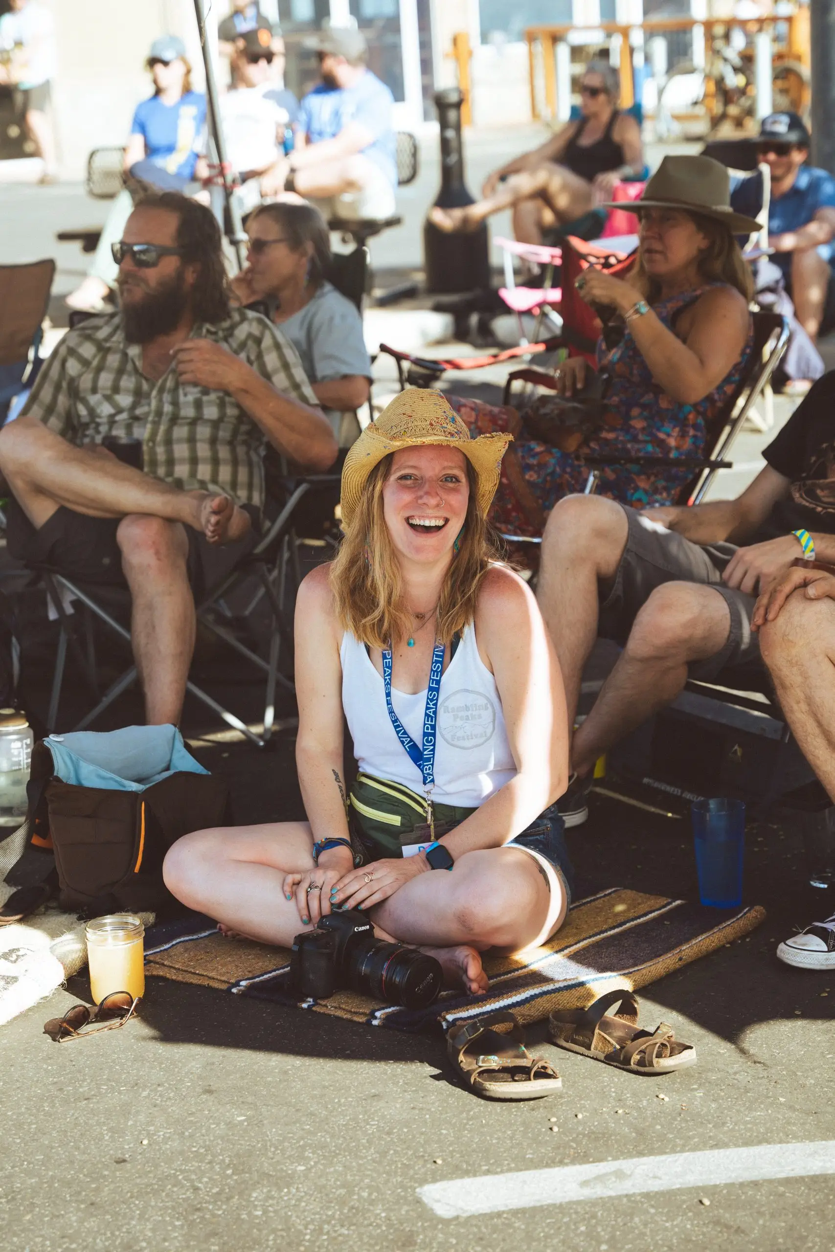 Woman sitting on the ground at Rambling Peaks Festival smiling at the camera.